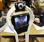 Devon Carrow attends Winchester Elementary School from home while operating a robot in the classroom, in West Seneca N.Y. Photo by David Duprey, Associated Press.