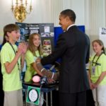 President Barack Obama grabs the steering wheel as Tristan Evarts, of Londonderry, N.H., explains how their invention can detect distracted driving as he tours science projects on display in the State Dining Room of the White House. (Official White House Photo by Chuck Kennedy.)
