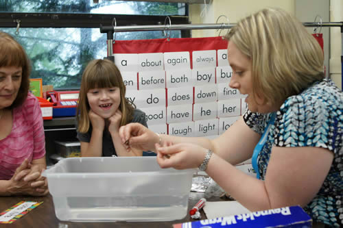 A little girl and her teacher working with manipulatives.