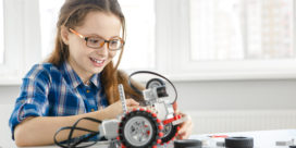 A picture of a girl playing with programmable robots for k-12 classrooms.