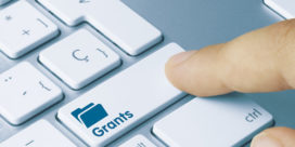 A person taps a keyboard key labeled "grants" in search of unique education grants.