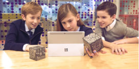 3 young students eagerly looking at a MERGE Cube, an AR app, with a laptop