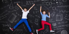 Two students jumping up and down on a blackboard with math problems