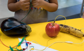 Students work on a fruit piano in a school makerspace.