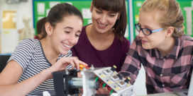 Three students work on a science robotics project in school as they participate in a school's coding or robotics program.