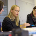 Three women sit and discuss what they're learning in a teacher preparation program.