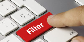 A finger presses a "filter" button on a keyboard, illustrating the importance of web filtering for schools.