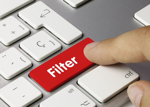 A finger presses a "filter" button on a keyboard, illustrating the importance of web filtering for schools.