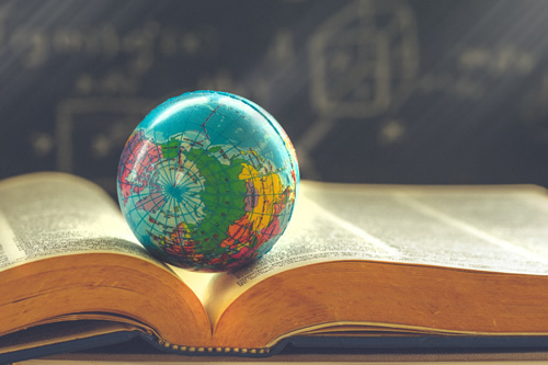 A globe sitting on a textbook illustrates the idea of global learning and SEL.