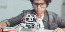 A student sits in front of a robot in a K-12 robotics and programming class.