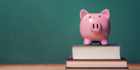 Check out these classroom grants if you or your school are in need of a funding boost or additional resources, like this piggy bank sitting on books in a classroom.