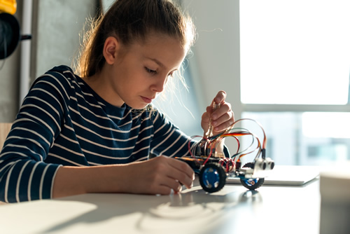 A young girl works on a robot, illustrating the growth of robotics education in the nation.