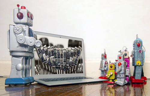 Robots standing in front of a laptop show how robots can help students with storytelling.
