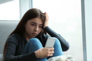 A tech director shares how monitoring software helps his schools stay on top of cyberbullying, like this upset teenage girl looking at her phone.