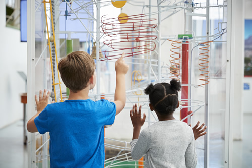 Science classes don't have to be a struggle--these citizen science lessons help students collaborate with real-world STEM professionals, like these two students looking at a science exhibit.