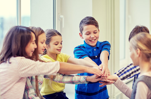 A new report breaks down the components needed to boost student engagement and create a more engaging learning experience like these students in a circle joining hands.