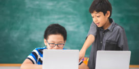 These two boys on laptops in a classroom demonstrate how 1:1 initiatives can be successful.