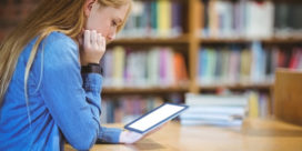 A report takes a look at some of the digital learning tools and strategies shaping the next calendar year, like this student sitting in the library with a tablet.