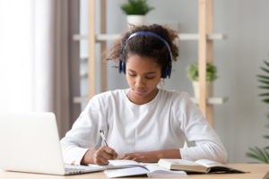 High-quality and engaging online learning programs have a number of common characteristics, like this young girl sitting learning online at her laptop.