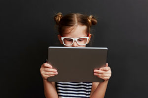 A child sits reading on her tablet.